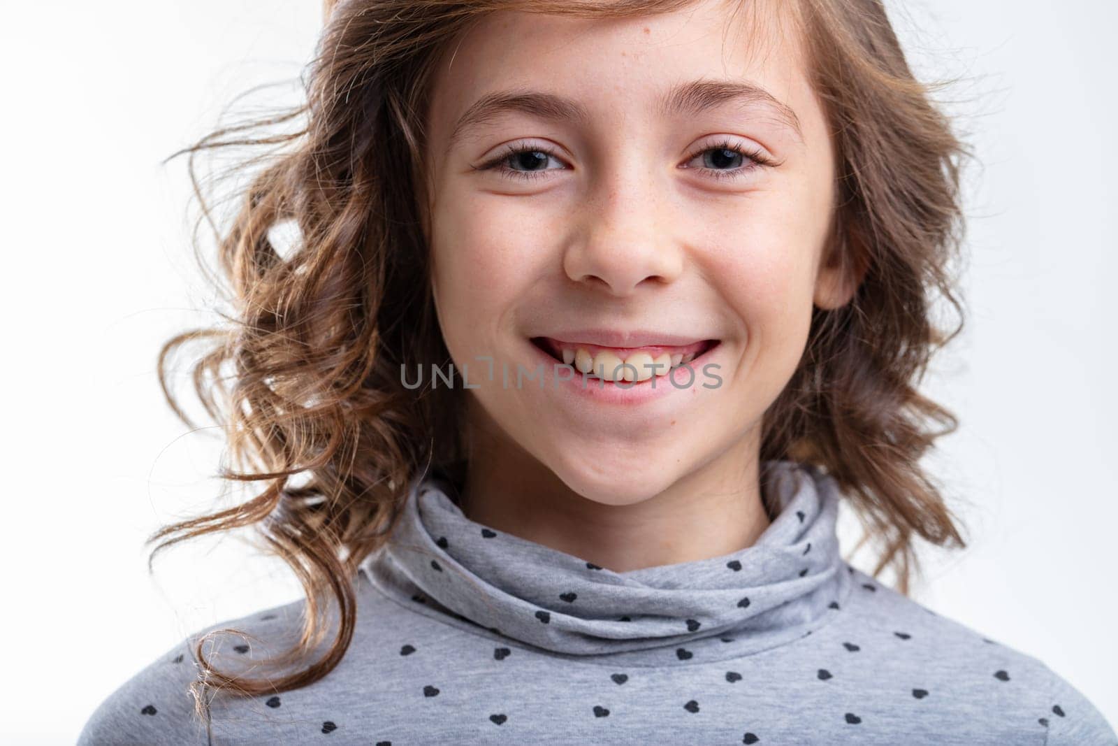 Cute little girl with a charismatic grin isolated on white in a close up cropped head shot as she smiles into the camera