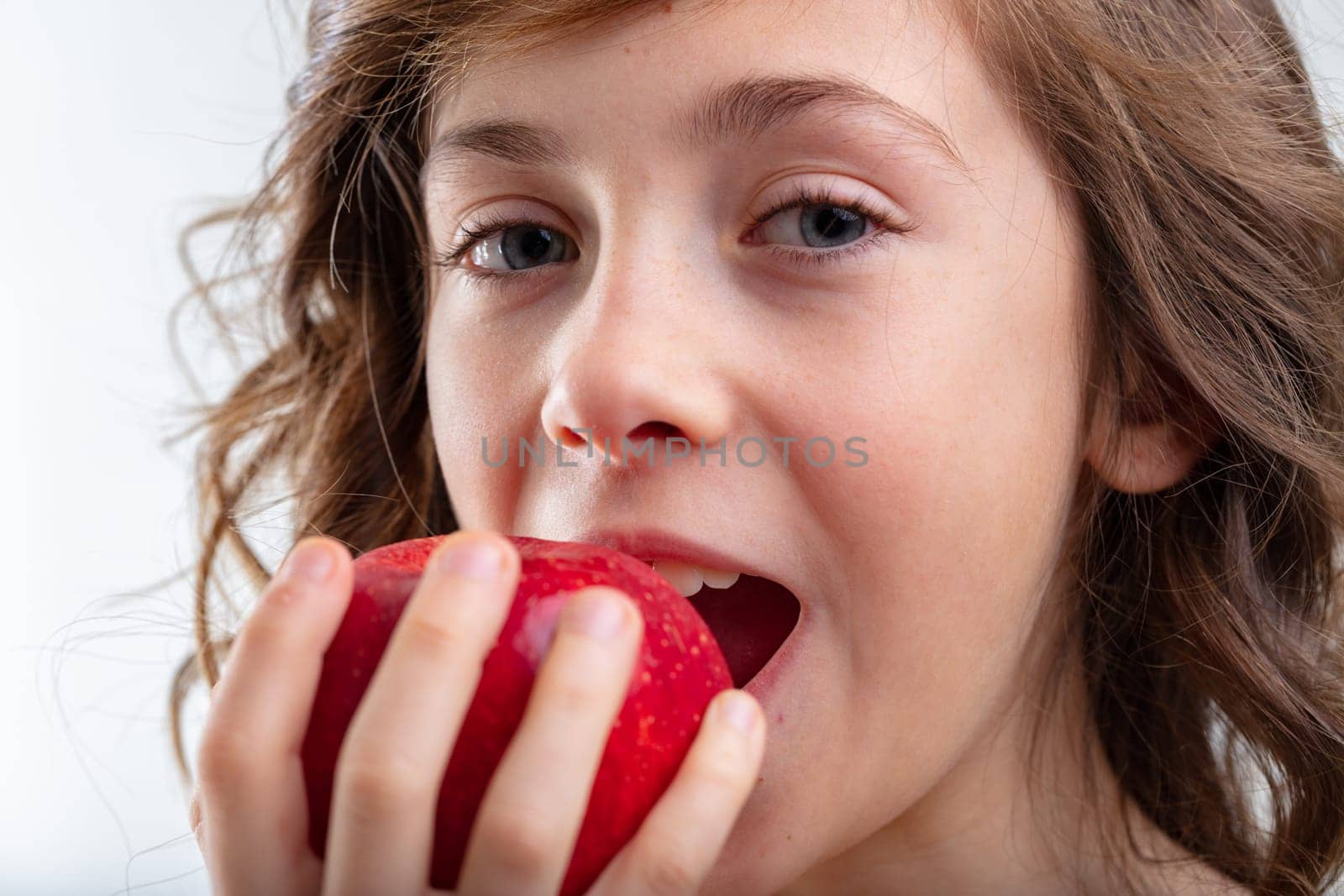 Young schoolgirl about to bite into a luscious red apple in a close up cropped sensual view in a healthy eating and diet concept