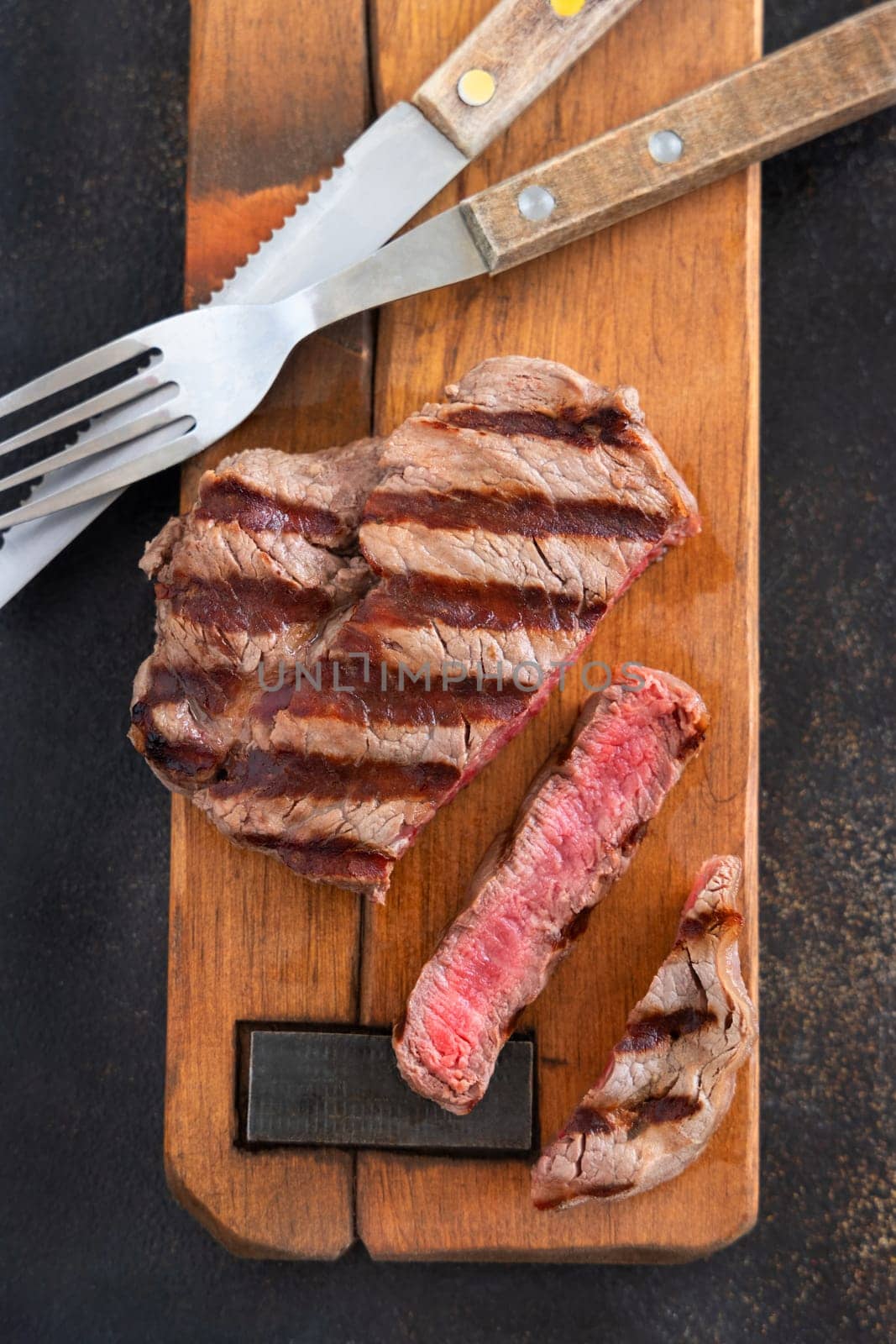 Grilled beef fillet steaks on dark table close up top view. Cooked Portioned filet mignon. Concept of summer food, meat eaters.