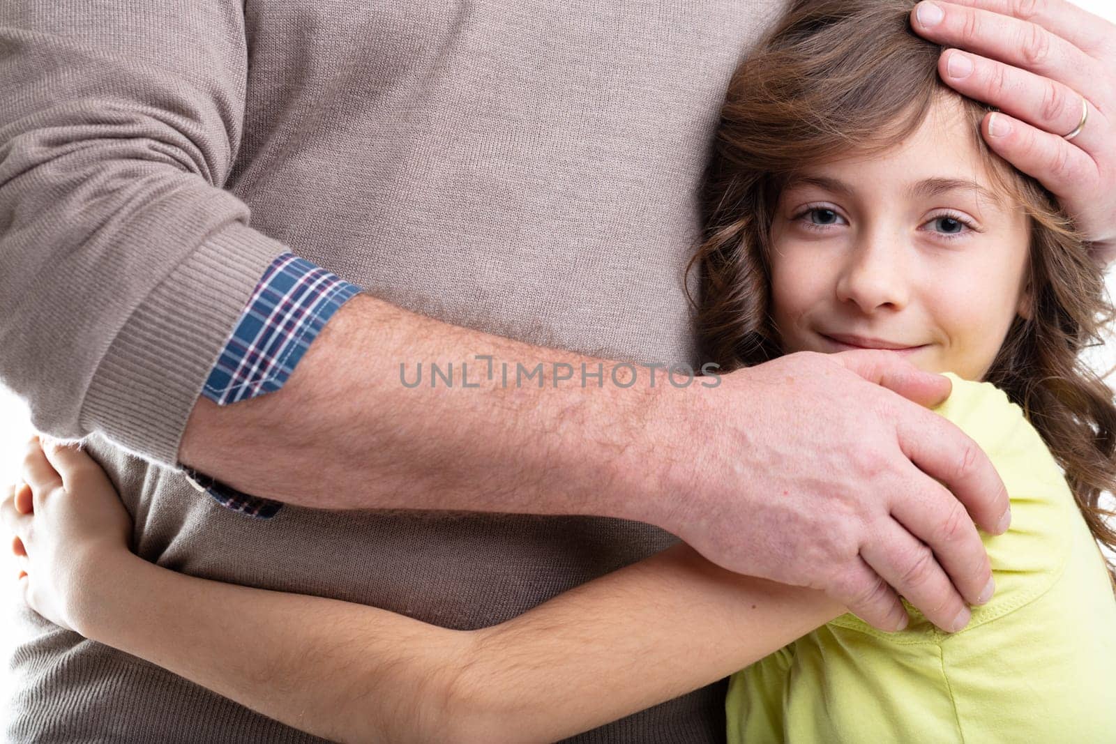 Pretty little girl hugging her father round the waist as he caresses her head in a concept of family love and parening