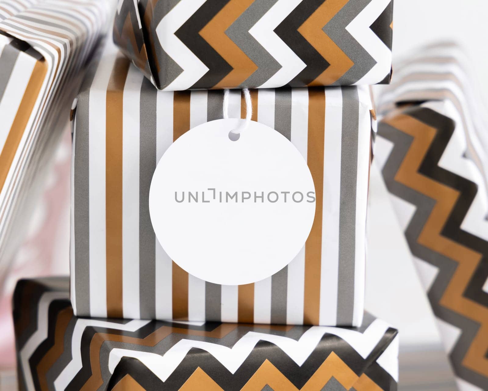 Present with blank round gift tag close up. Gift boxes wrapped in Striped and chevron geometric paper. Christmas, New Year, Birthday, Anniversary label mockup