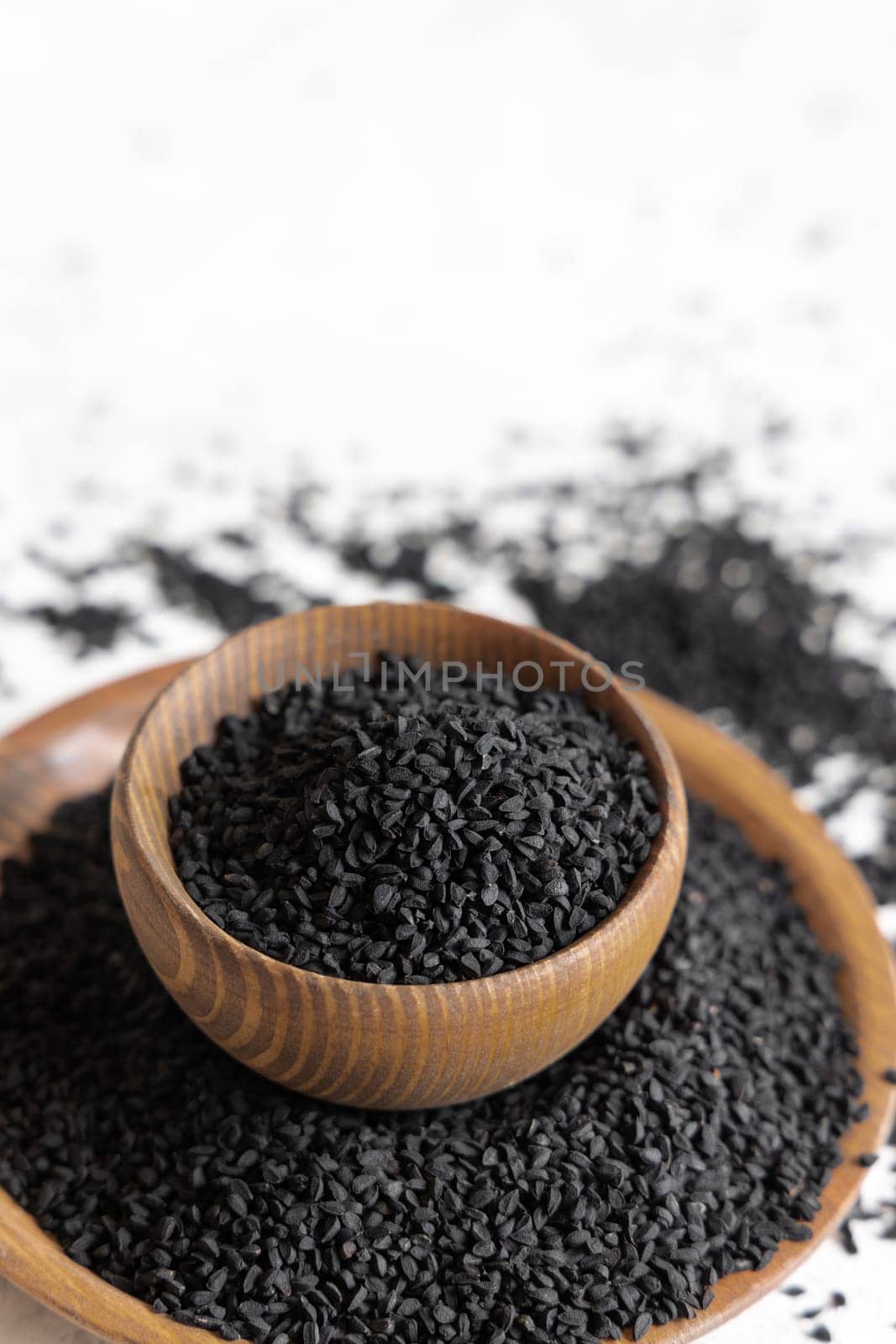 Indian spice Black cumin (nigella sativa or kalonji) seeds in wooden bowls close up with copy space. Traditional medicine, healthy and vegetarian food concept.
