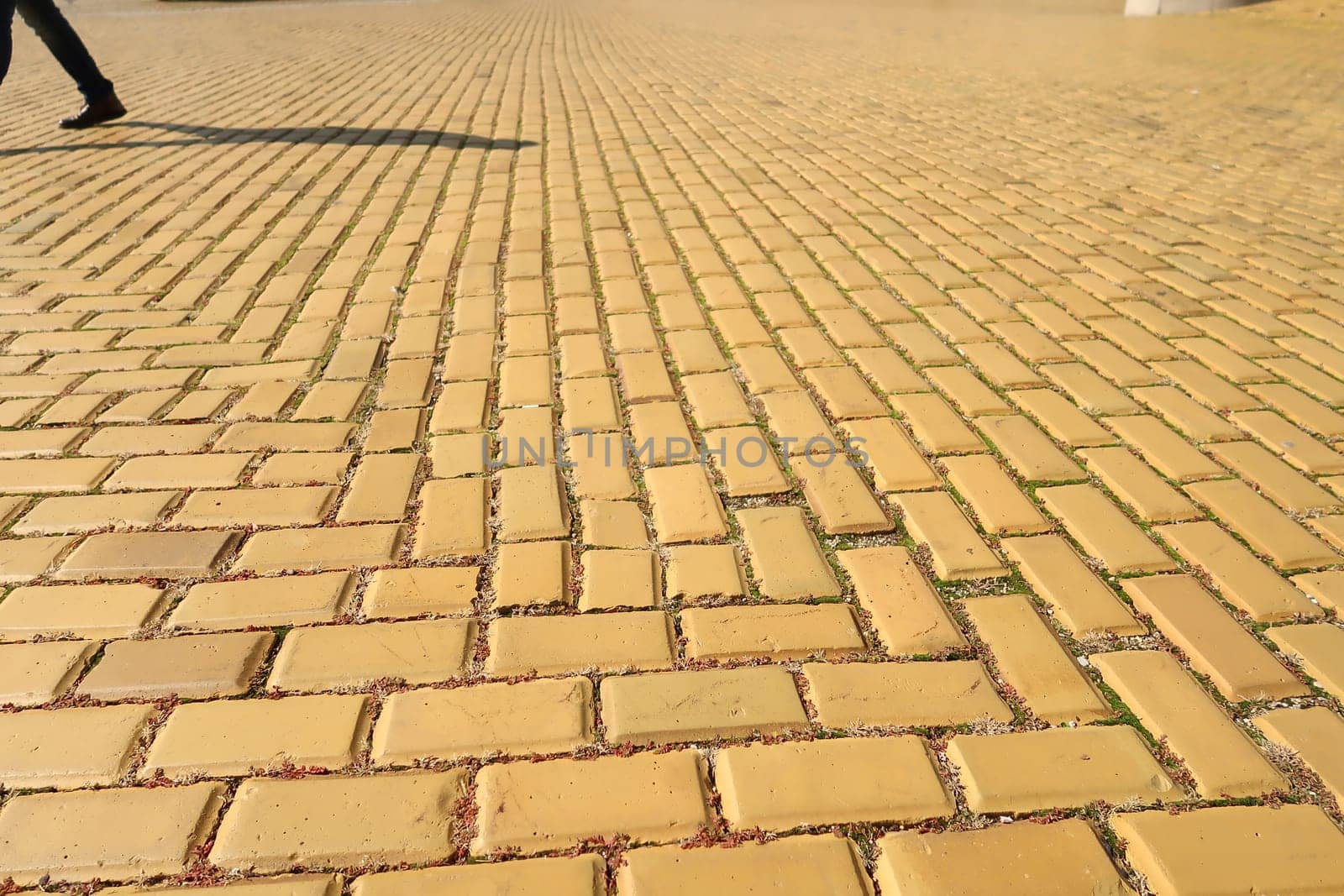 Yellow cobblestone, brick road in Sofia, shadow of pedestrian in the background, Bulgaria 2021