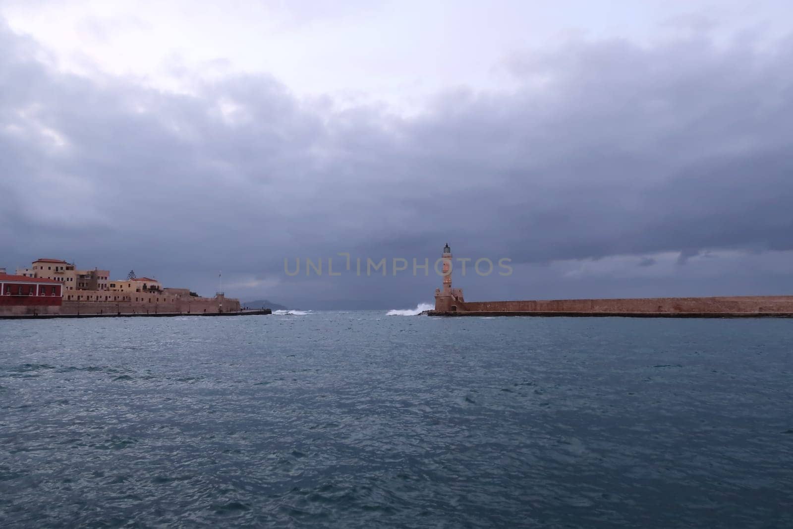 Chania's seafront onto the water and it's lighthouse at a cloudy day in fall, Crete, Greece 2021