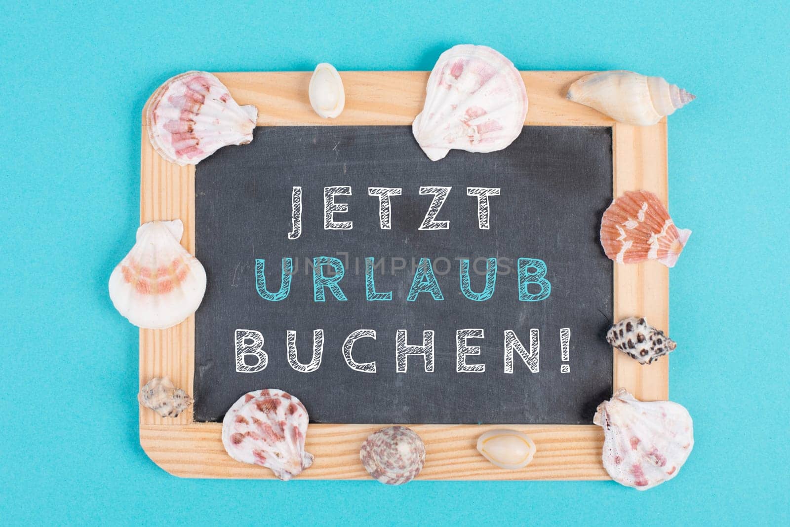 Book vacation now is standing in german language on the chalkboard, seashells bulit frame, holiday and summertime topic, travel concept