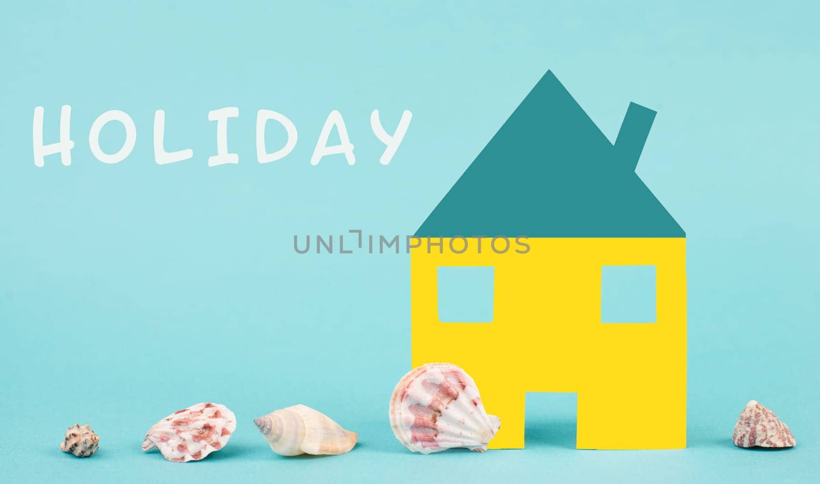 White house on a blue colored background with sea shells, booking an appartment, hotel or lounge for vacation, holidays in summer on the beach, copy space for text