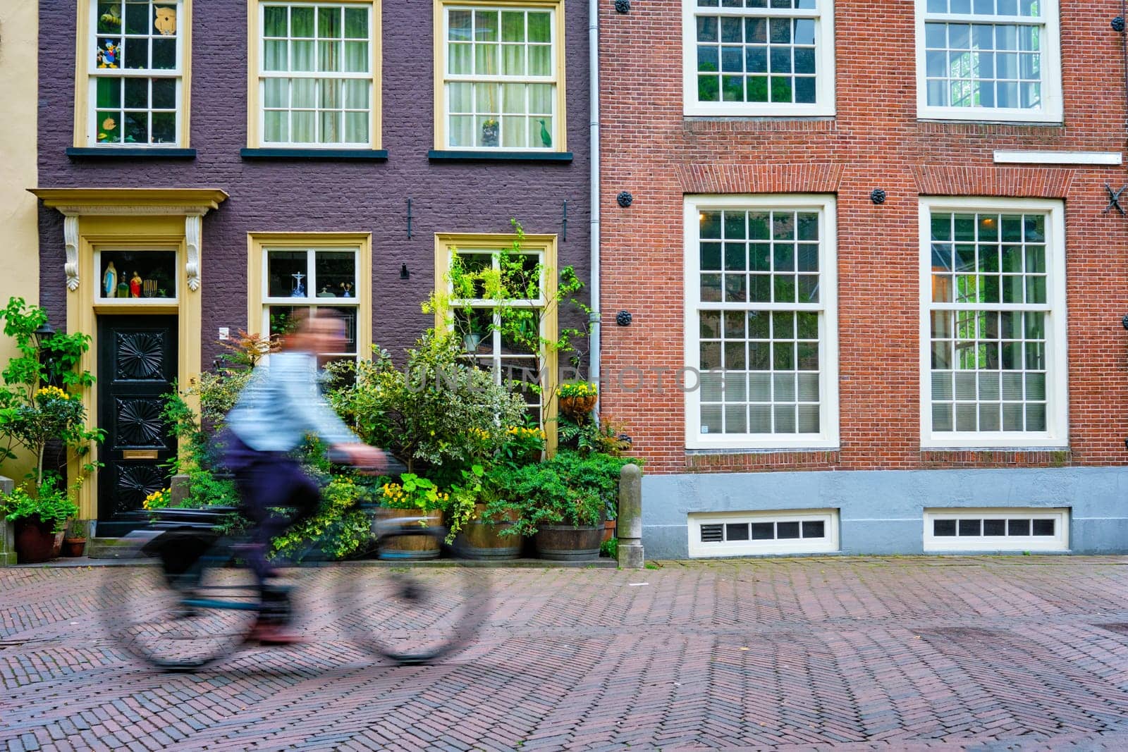 Motion blurred bicycle rider cyclist man on bicycle very popular means of transport in Netherlands in street with old houses of Delft, Netherlands