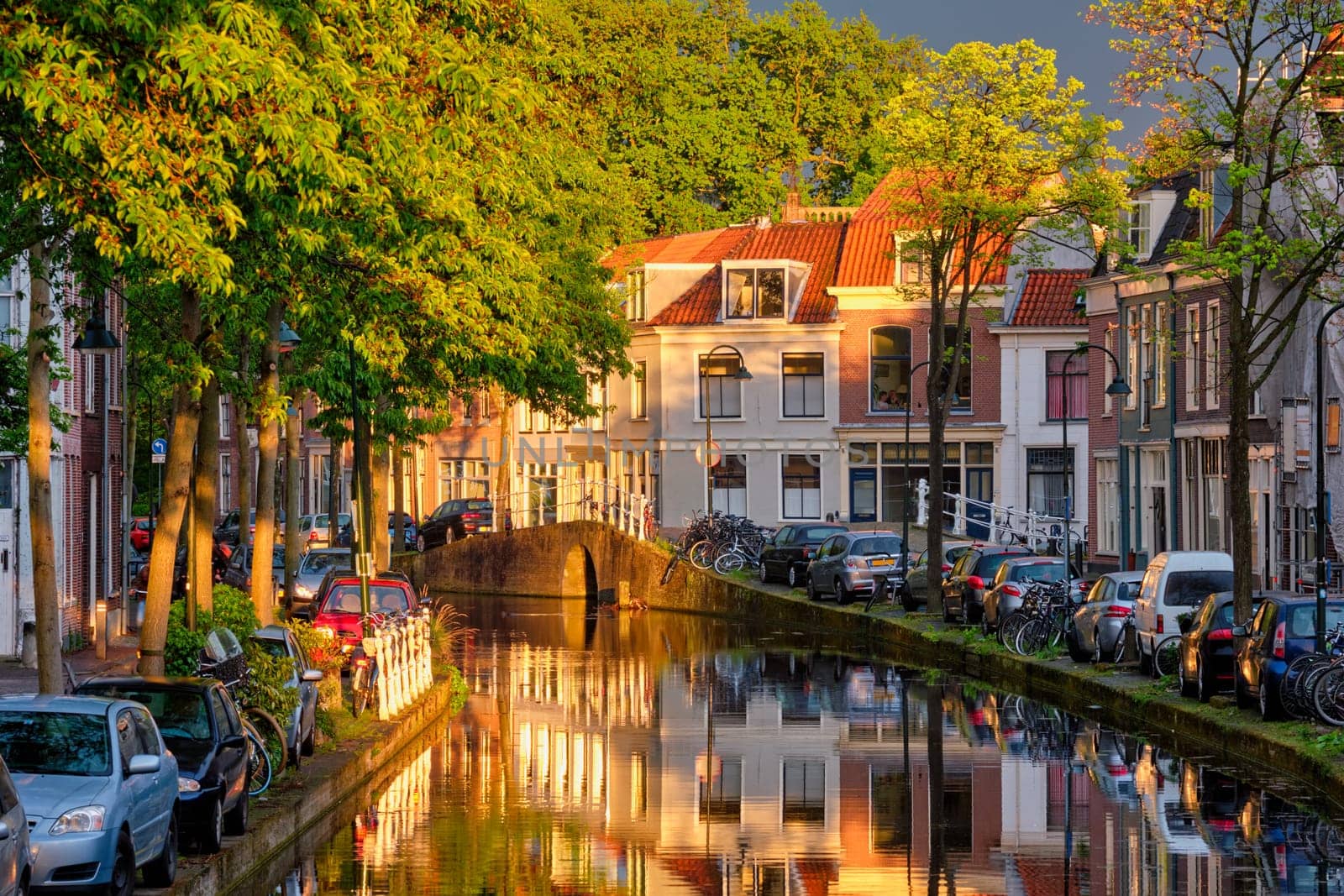 Delt canal with old houses and cars parked along on sunset. Delft, Netherlands