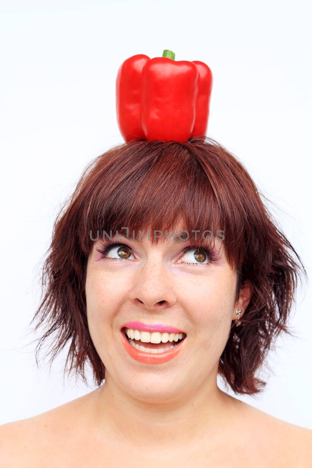 A laughing young woman with a red bell pepper on her head