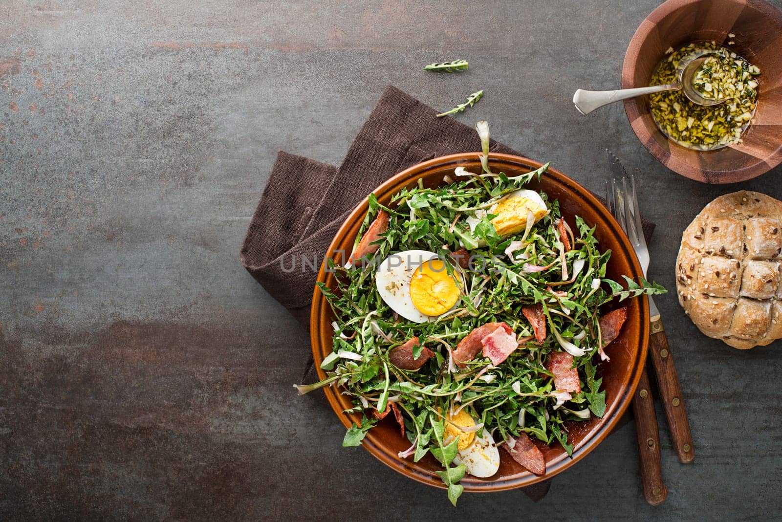 Dandelion salad with eggs and bacon on grey background