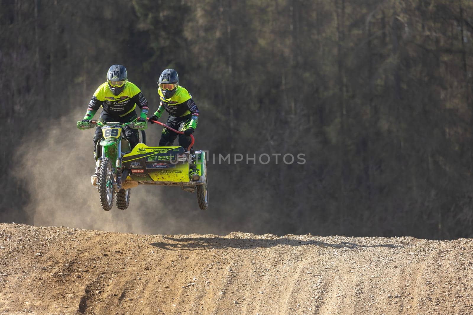 MOHELNICE, CZECH REPUBLIC - APRIL 16, 2022. Sidecacross riders jump with motorbike on a dark background in the "Sidecarcross Championship of Czech Republic"" on April 16, 2022 in Mohelnice, Moravia, CR"