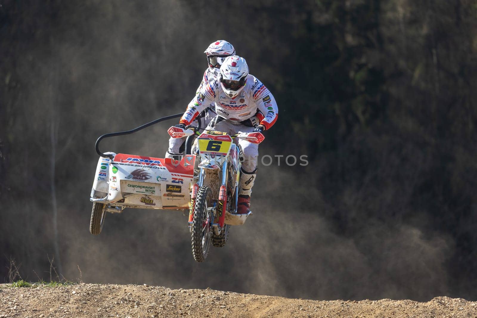 MOHELNICE, CZECH REPUBLIC - APRIL 16, 2022. The winners of the race are in a high jump on a dark background in the "Sidecarcross Championship of Czech Republic"" on April 16, 2022 in  Mohelnice."