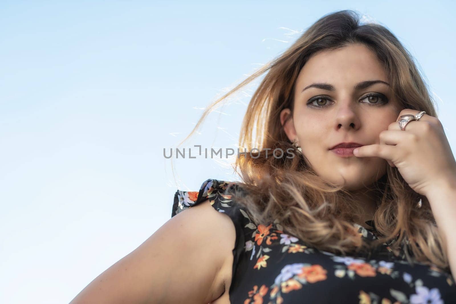 Portrait of beautiful  young woman posing outdoors against blue sky. Horizontally.
