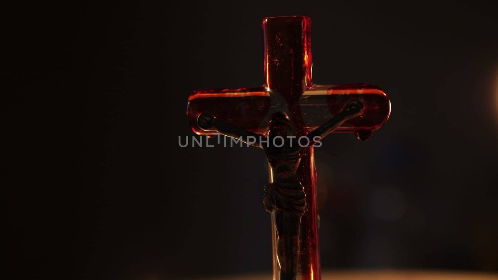 Close up of cross of jesus with blood lit by candle.