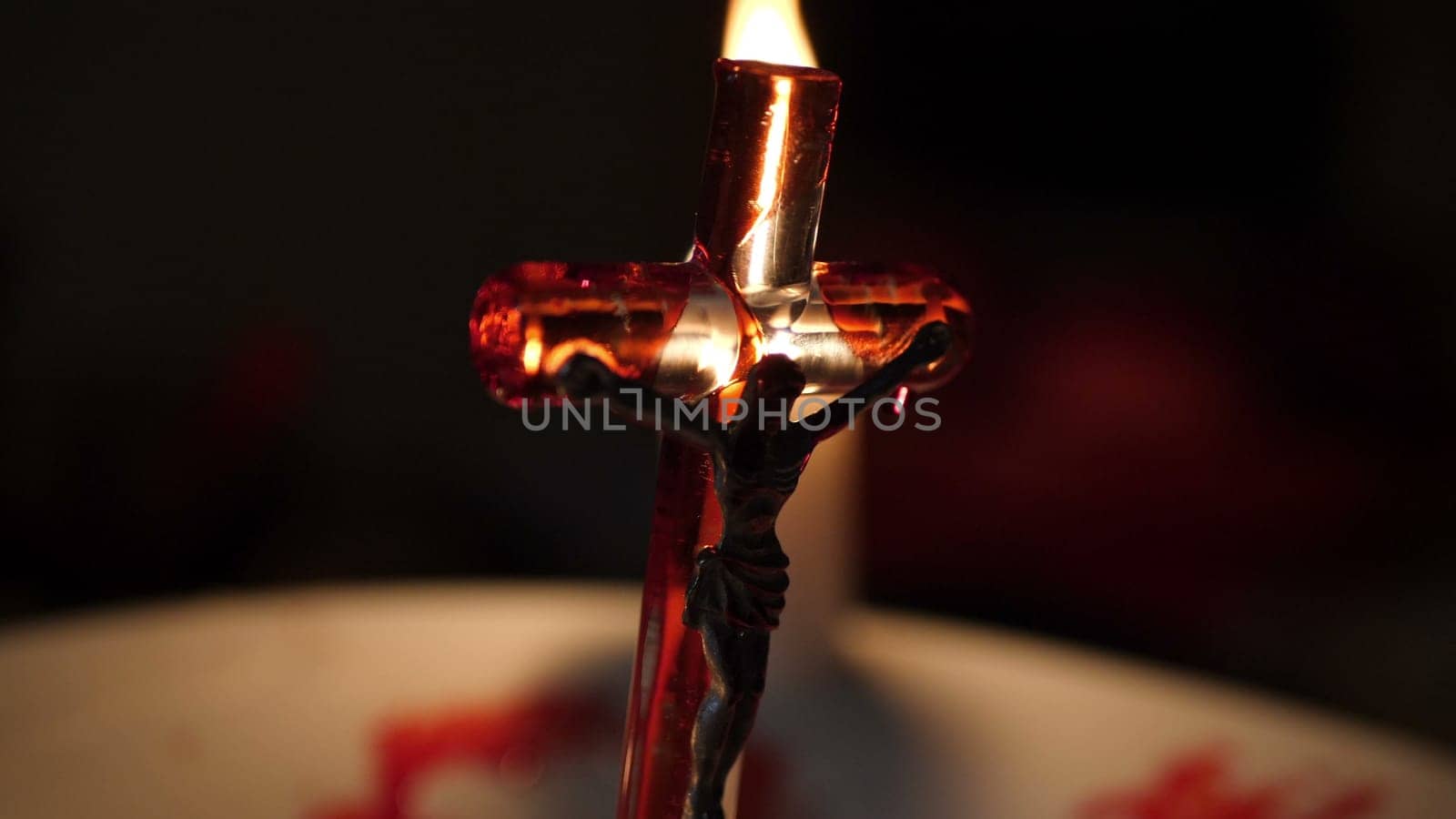 Close up of cross of jesus with blood lit by candle