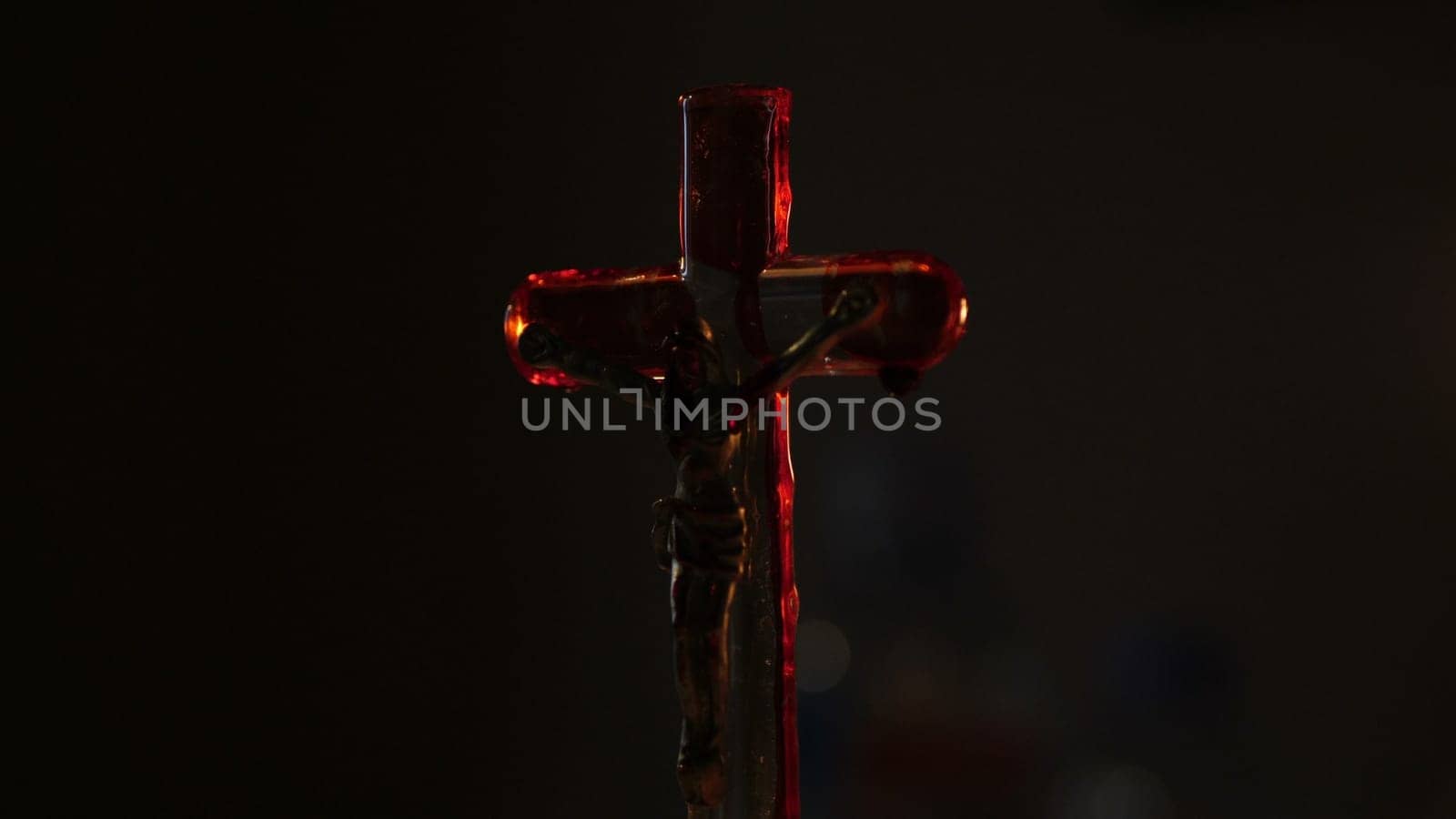 Close up of cross of jesus with blood lit by candle..