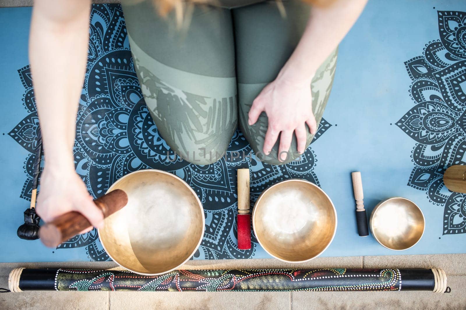 Yoga concept, meditation and sound therapy. Beautiful young caucasian woman surrounded by copper tibetan singing bowls and instruments