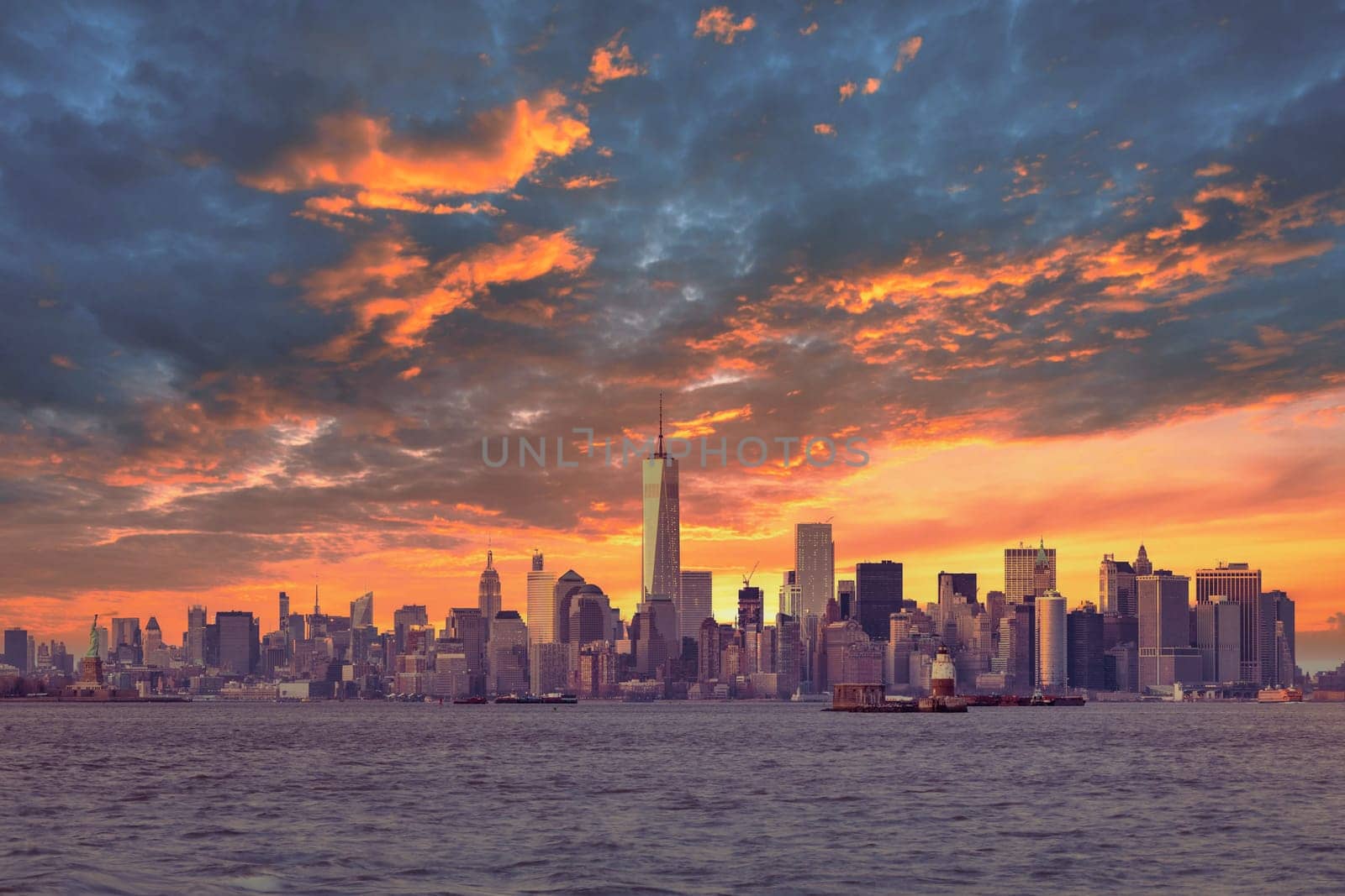 New York City Manhattan downtown skyline at dusk with skyscrapers illuminated over Hudson River panorama. Dramatic sunset sky
