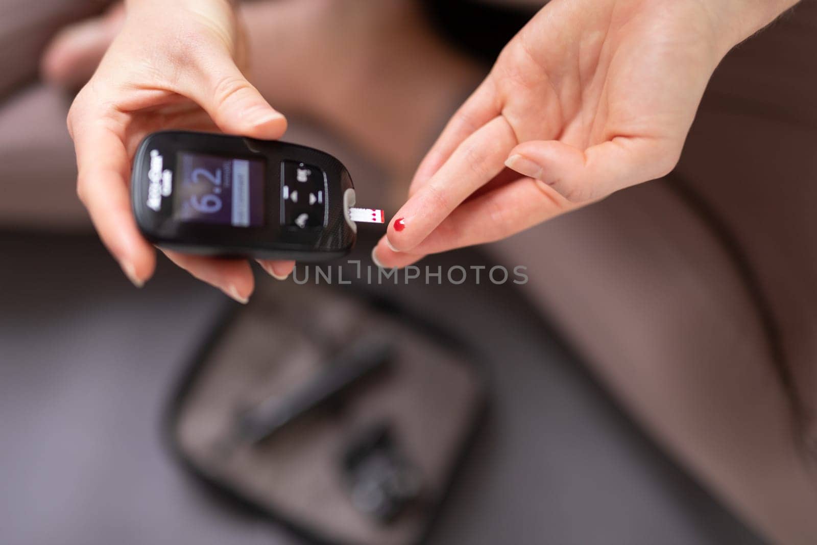 Blood sugar testing at home. Woman checking blood sugar level by glucometer and test stripe at home. Diabetic checking blood sugar levels