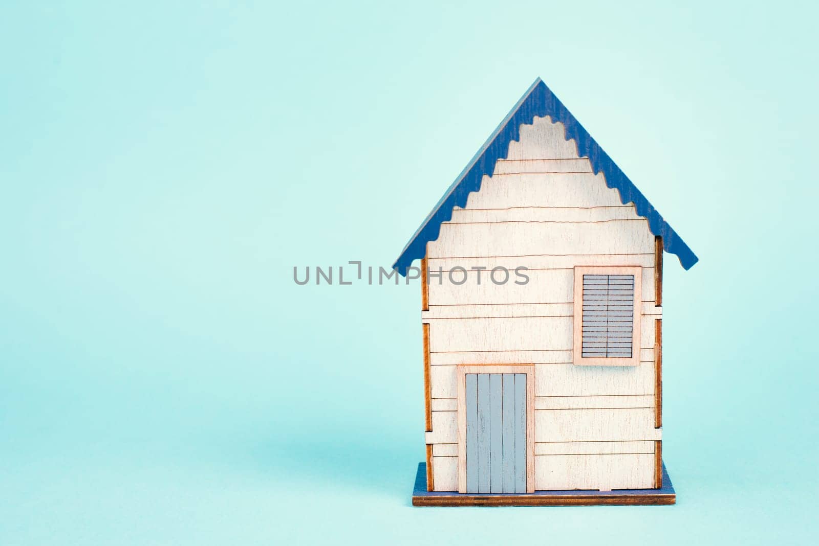 Wooden house, blue background, buying or renting a house, real estate concept, booking home for vacation, copy space for text
