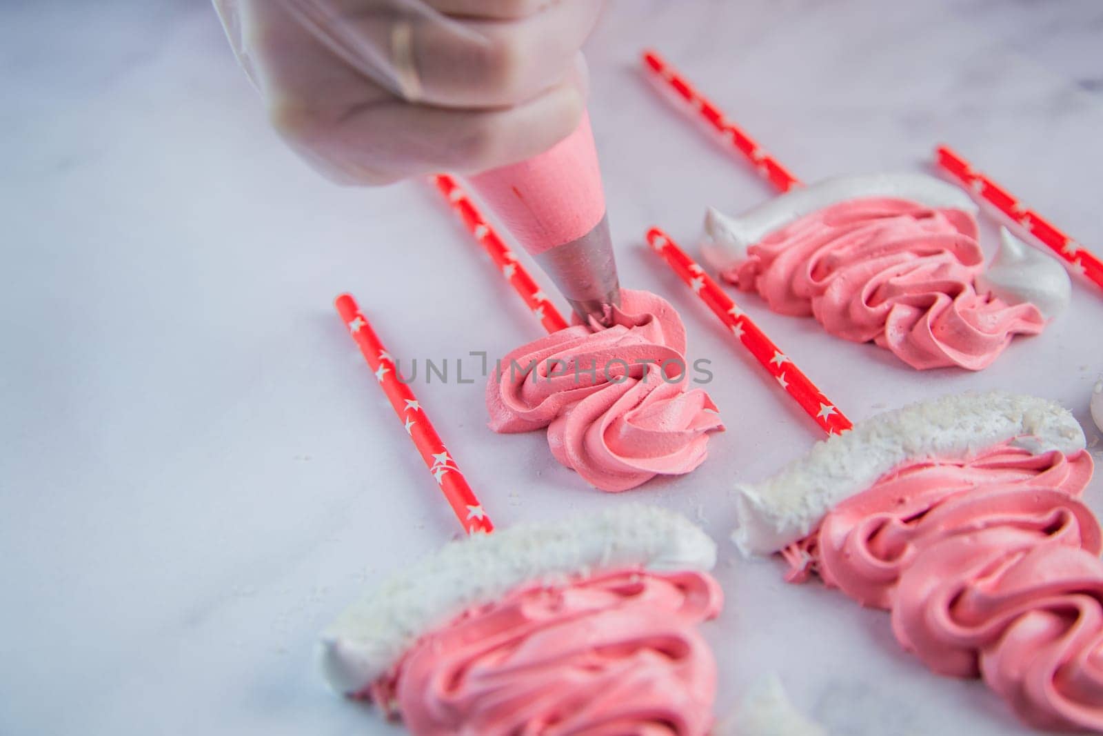 From the pastry bag, the pastry chef squeezes out a zigzag meringue on white parchment and a red stick. High quality photo