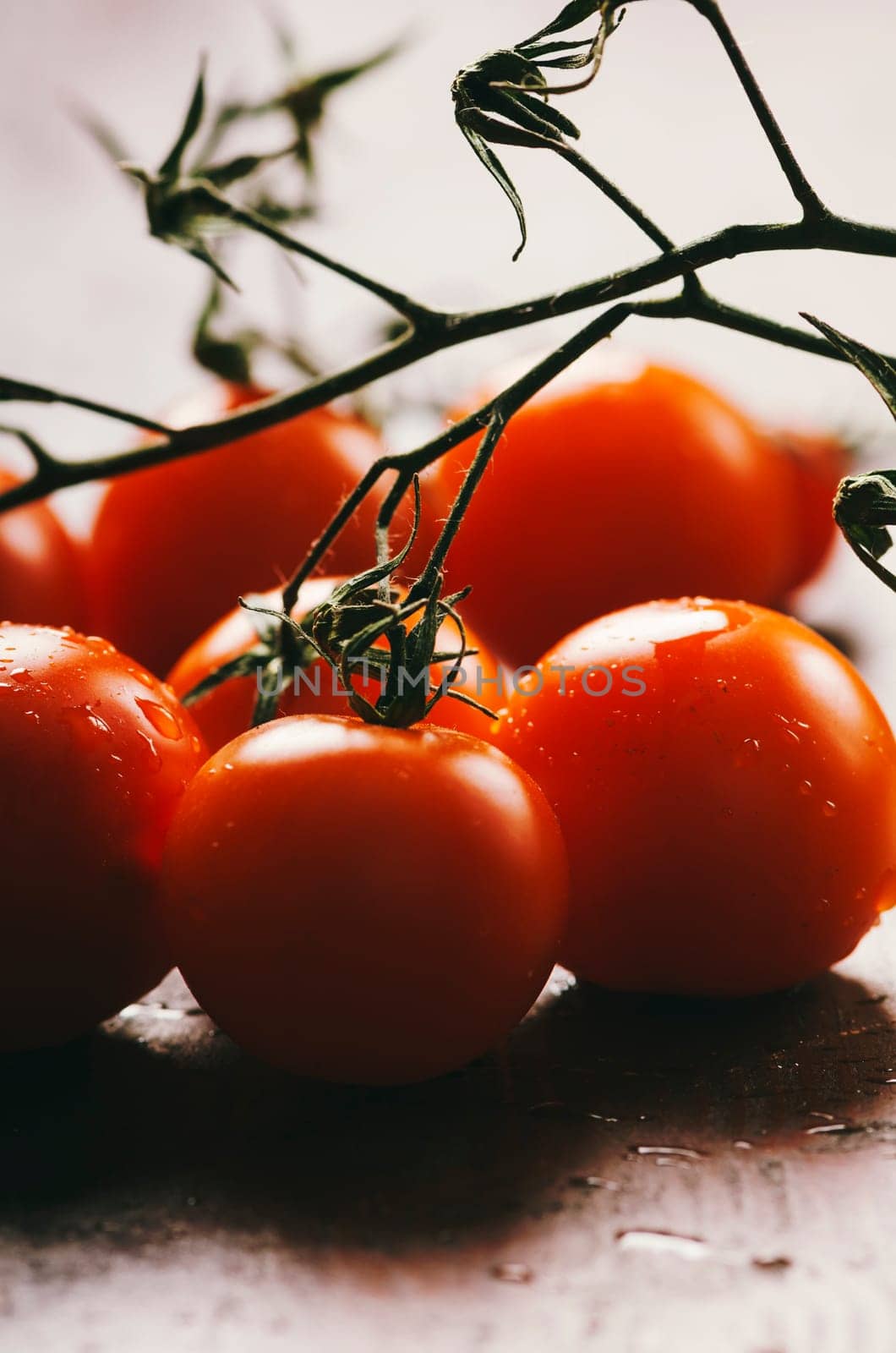 Cherry tomato with water drops on rustic wooden table.