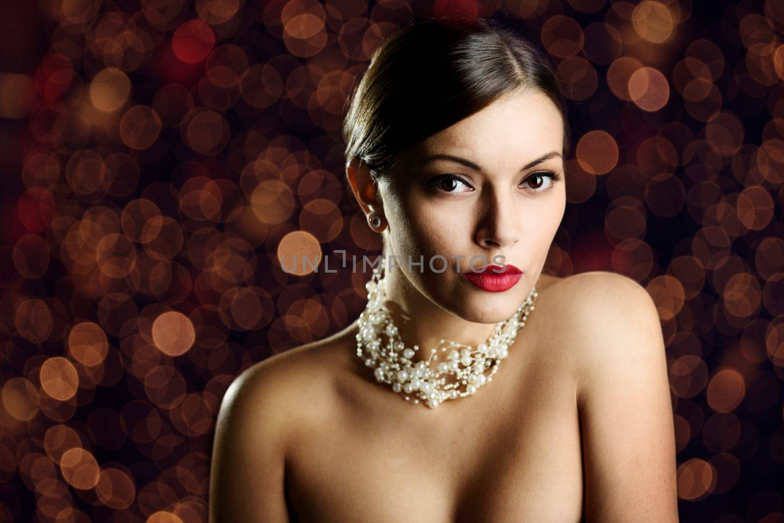Beautiful young woman with elegant makeup and pearls in front of night lights.