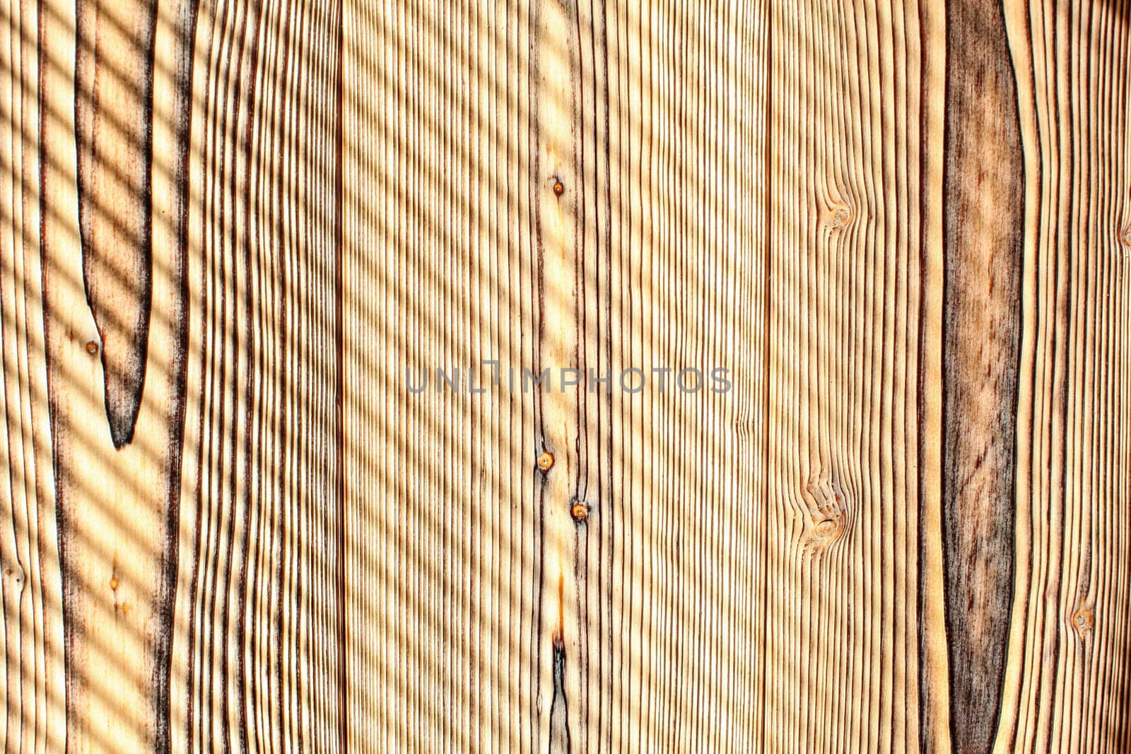 Desk made from wooden boards lit by morning sun, shades leaving diagonal stripes pattern