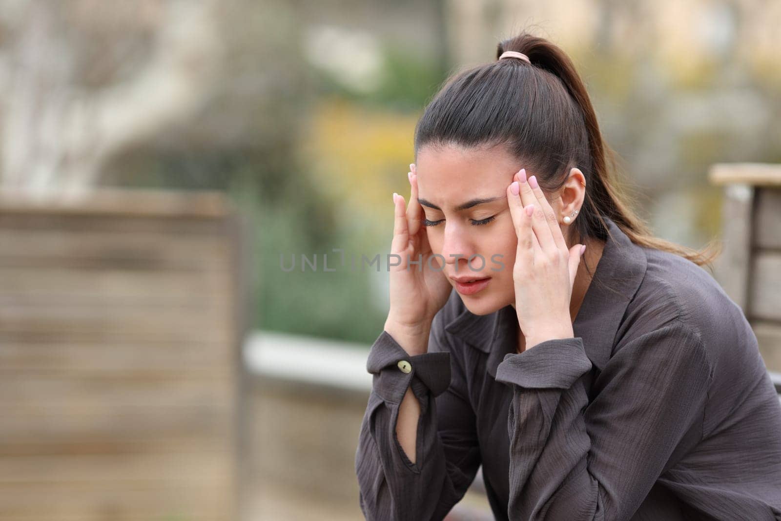 Teen suffering migraine complaining sitting on a bench