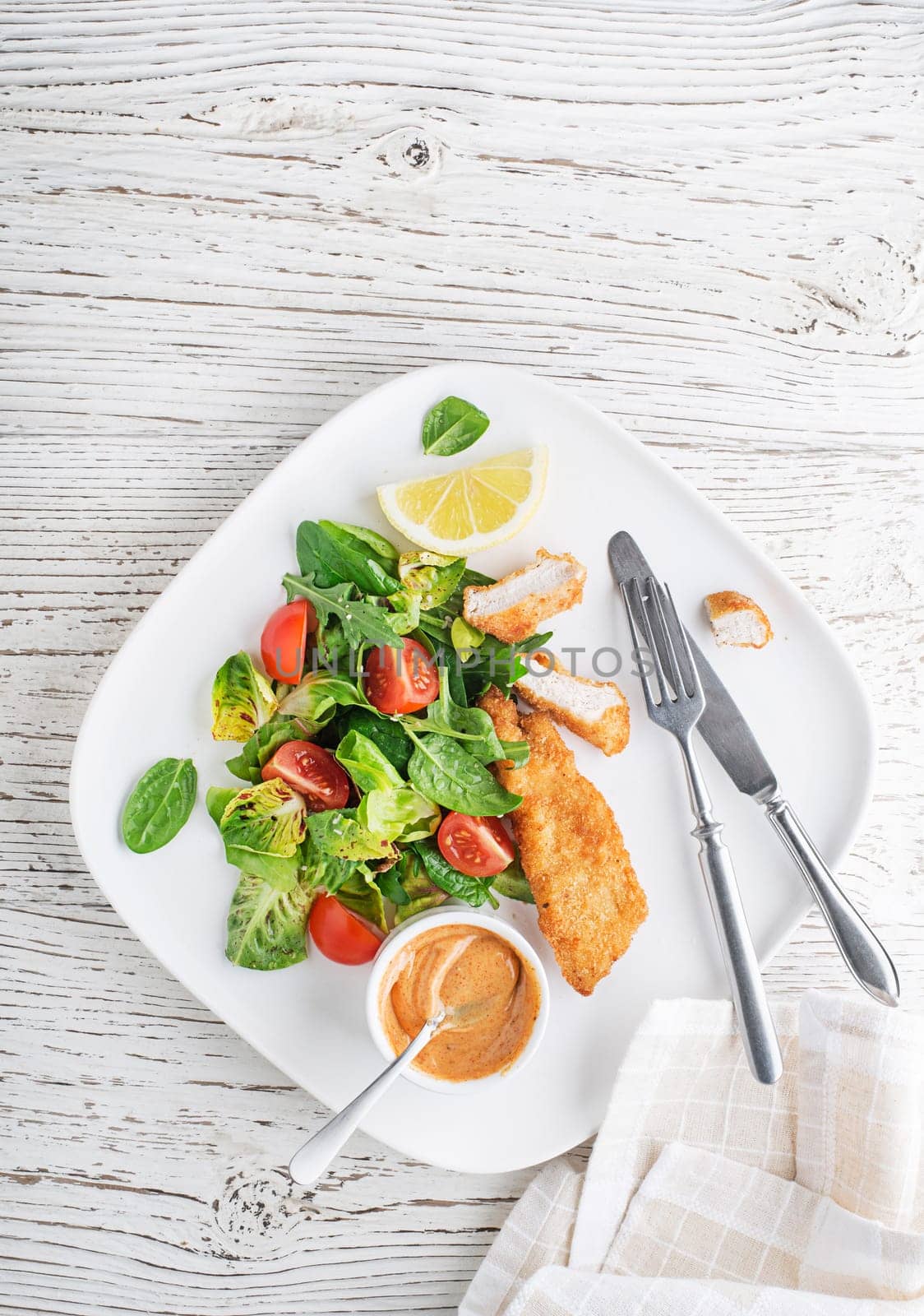 Crispy chicken steaks with green salad and tomato. Fried chicken meal with vegetables