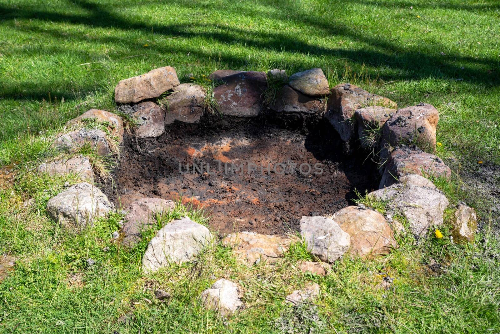 rustic stone circle fire pit in sunny grass background
