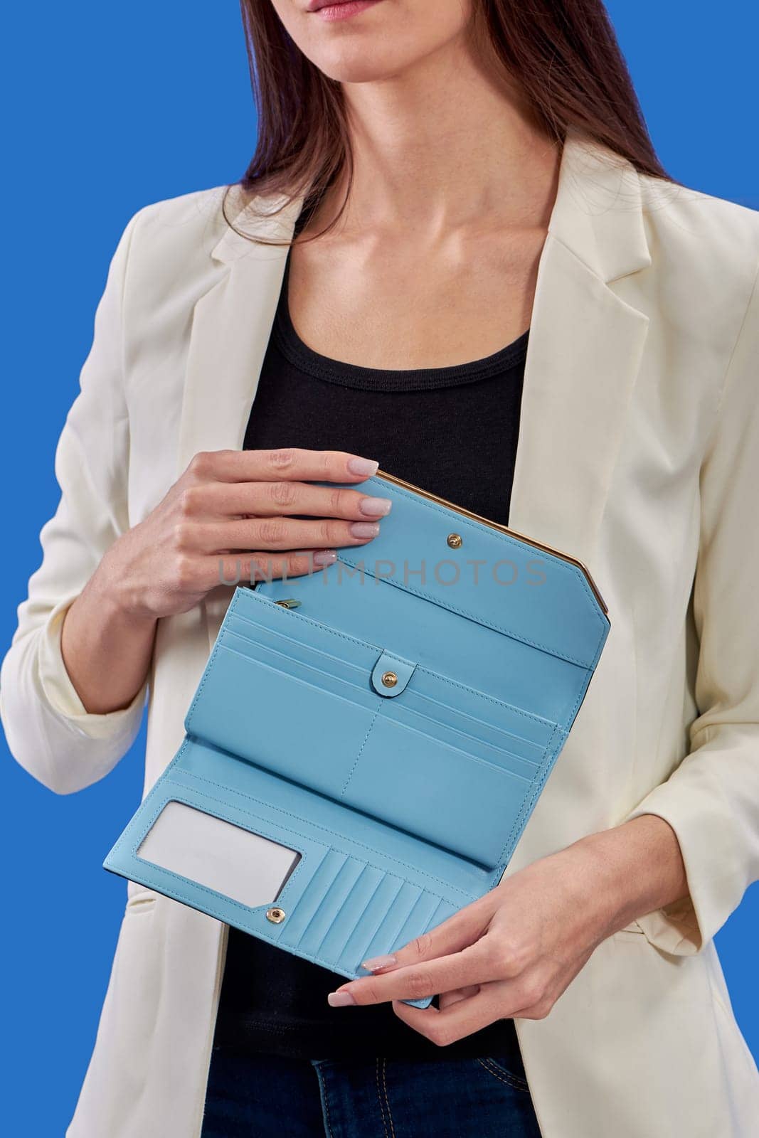 A beautiful young woman is holding a blue purse on a blue background. High quality photo