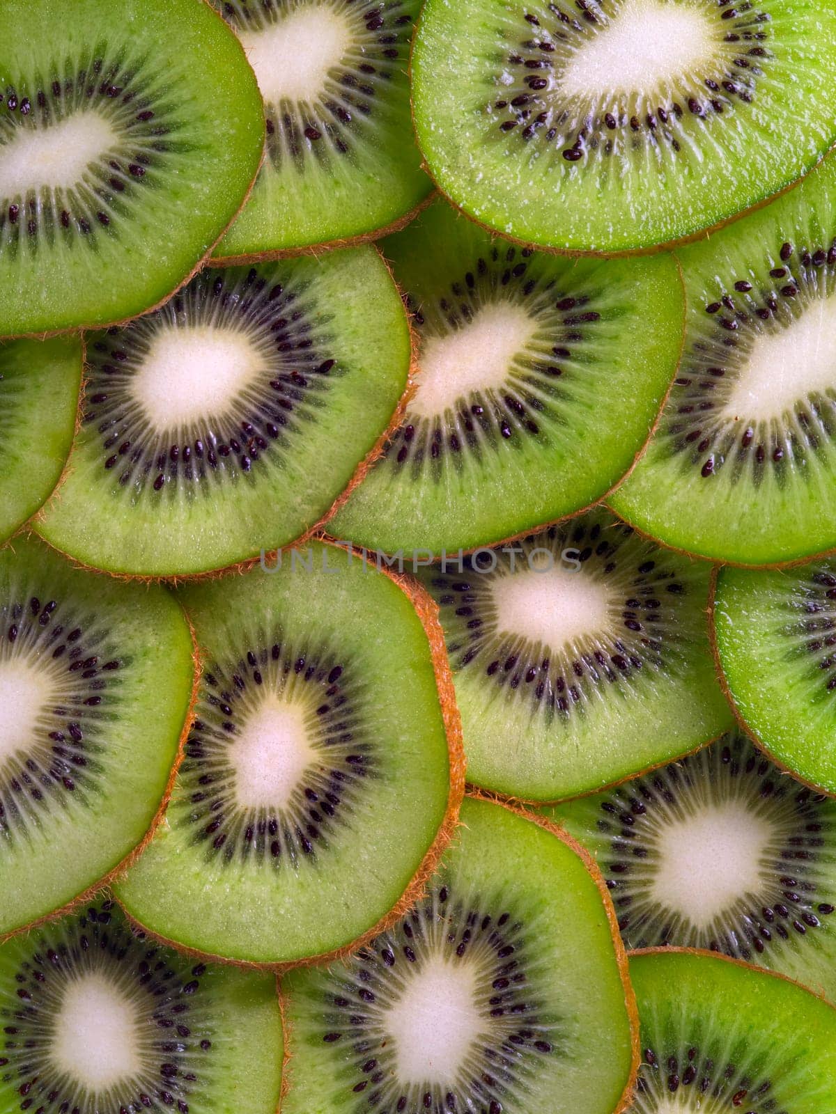 Background of juicy kiwi fruit thinly sliced and overlapping.