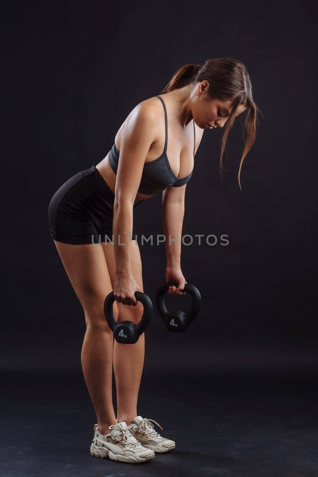 Young sexy woman exercising and lifting kettle bells.