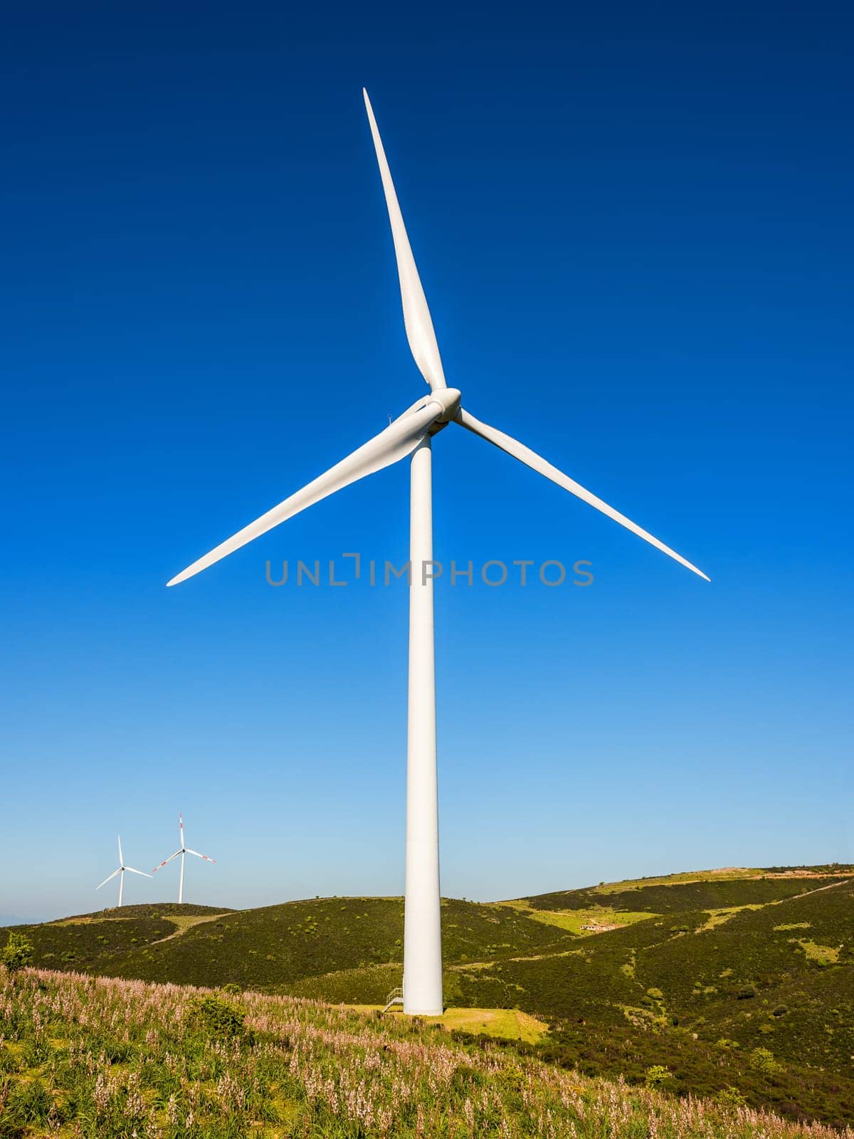 Wind turbines on a beautiful blue sky in a mountain wind farm in Sardinia. Renewable energy concept, green energy generation. Energy industry.