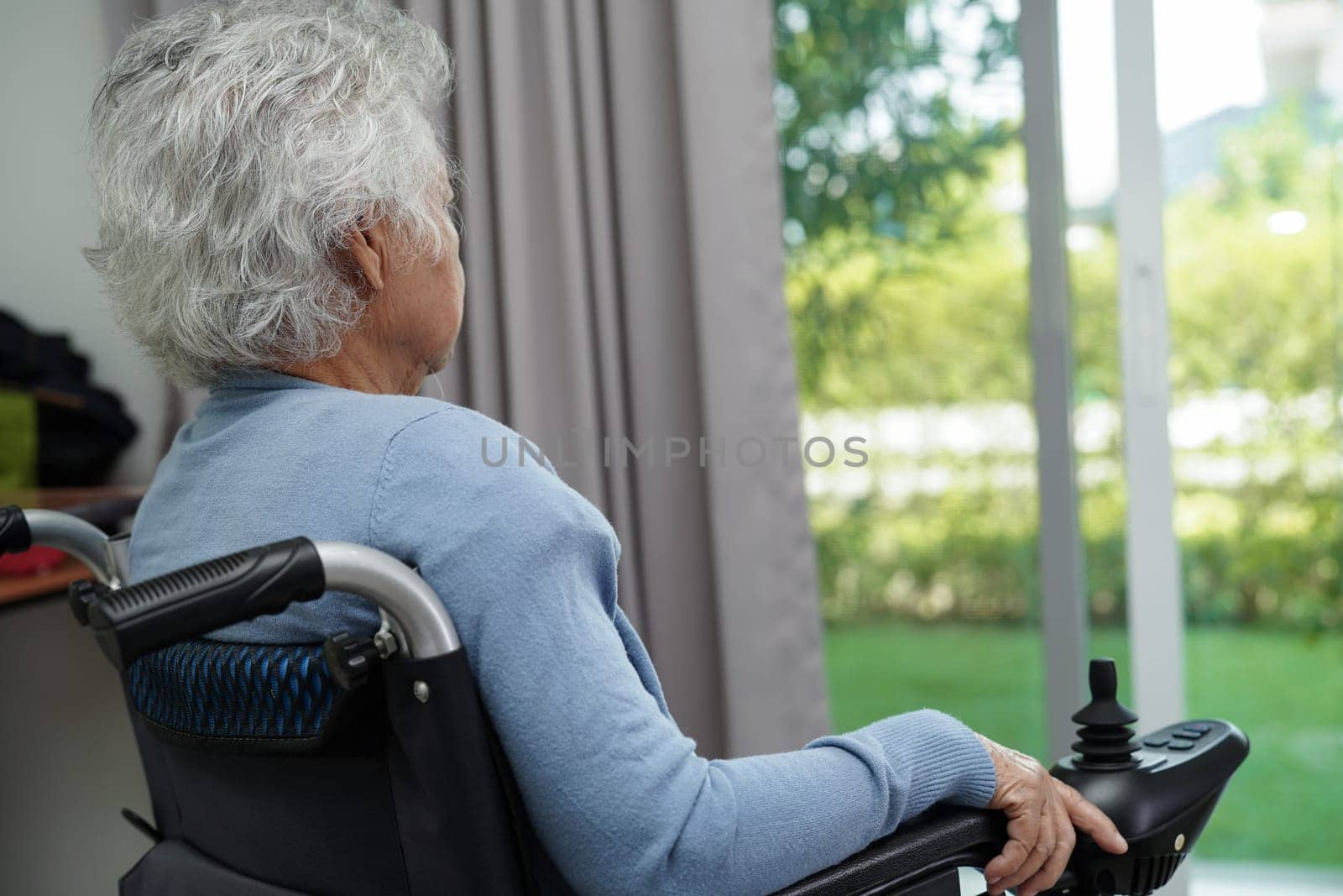Asian elderly woman disability patient sitting on electric wheelchair in park, medical concept.
