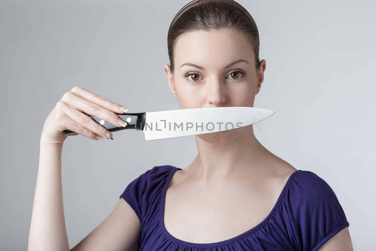 A young woman is playing with a sharp kitchen knife