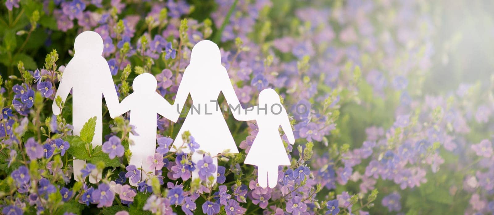 Family paper cut out is standing in a meadow, parents with daughter and son, environment concept, spring and summer season