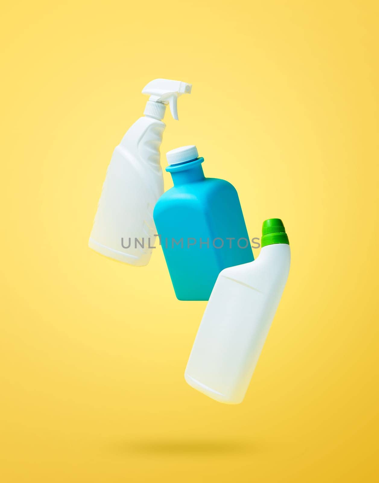 Levitation, falling in air blank household chemical bottles for cleaning the house. Isolated on yellow background. Plastic packaging. Toilet cleaner, detergent sprayer, soap. New brand product mockup