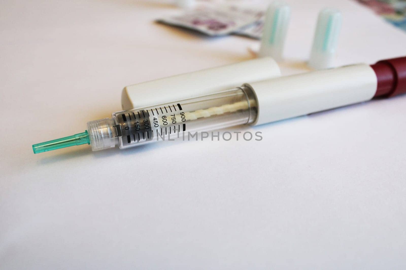Injection syringe on a white table with spare needles in the background. Diabetes mellitus..
