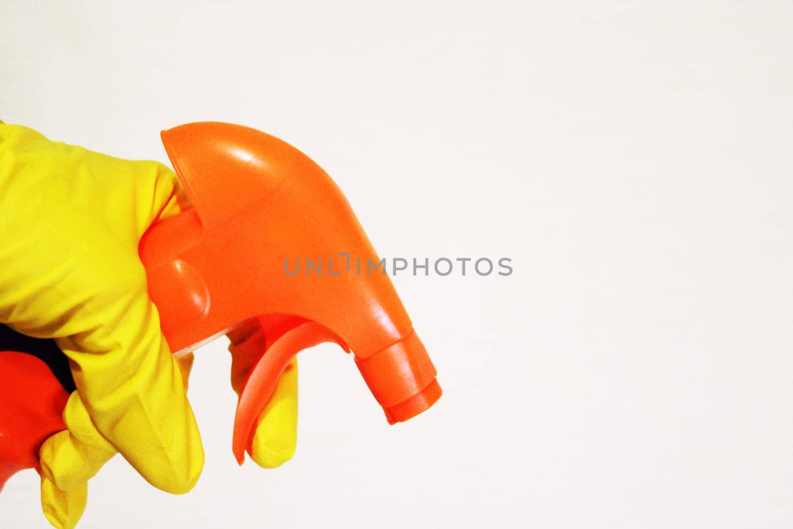 Image of a hand wearing a rubber glove with a cleaning spray. The concept of purity..
