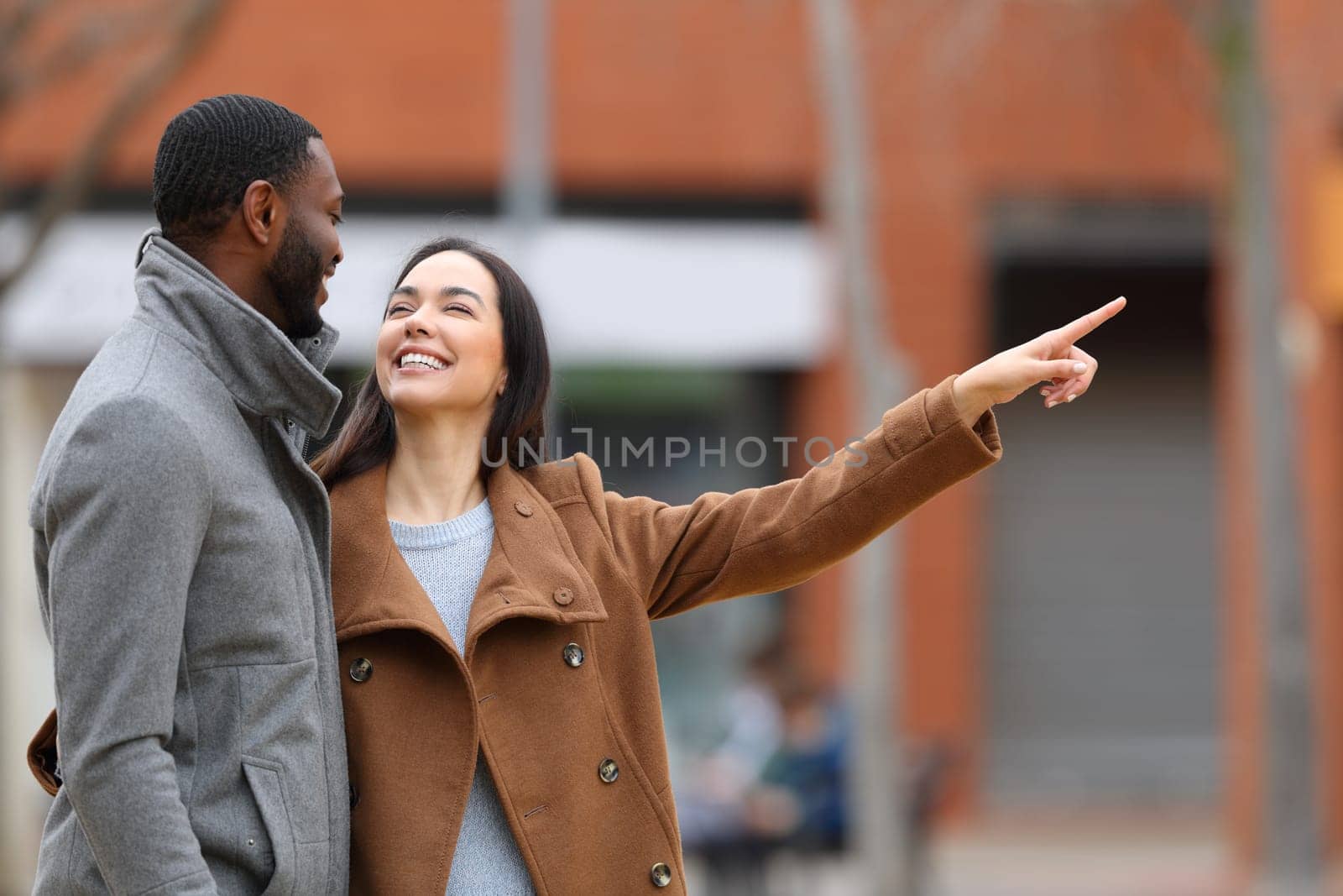 Interracial couple talking and pointing in the street