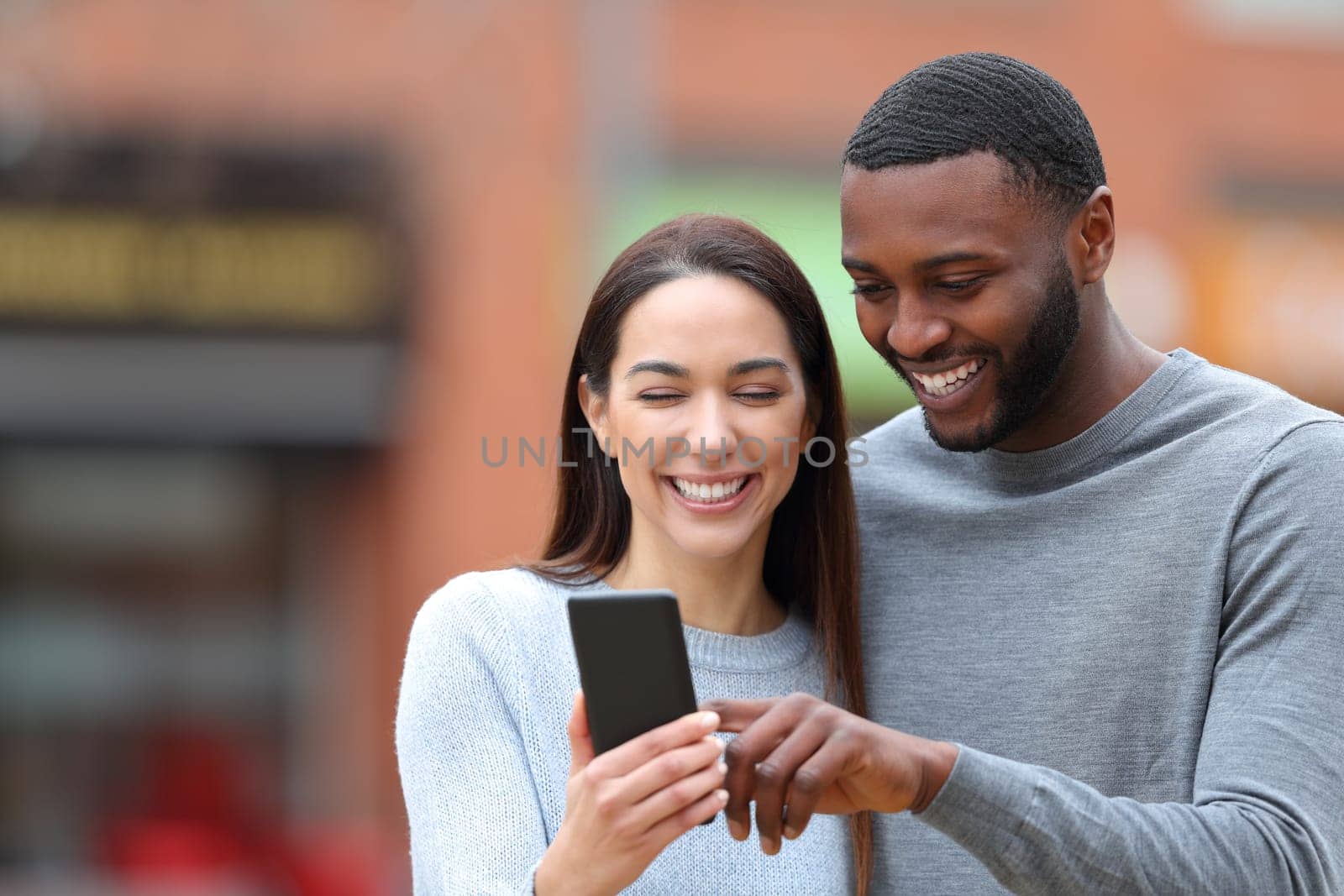 Happy interracial couple consulting phone text
