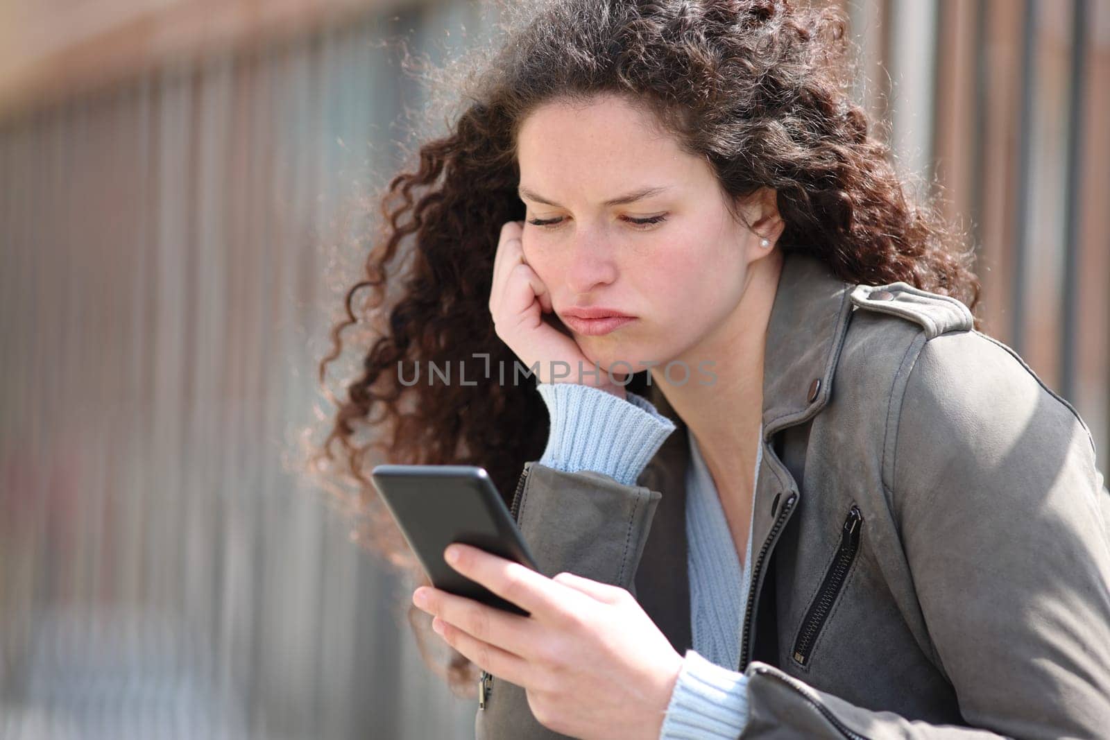 Bored woman checking smart phone in the street