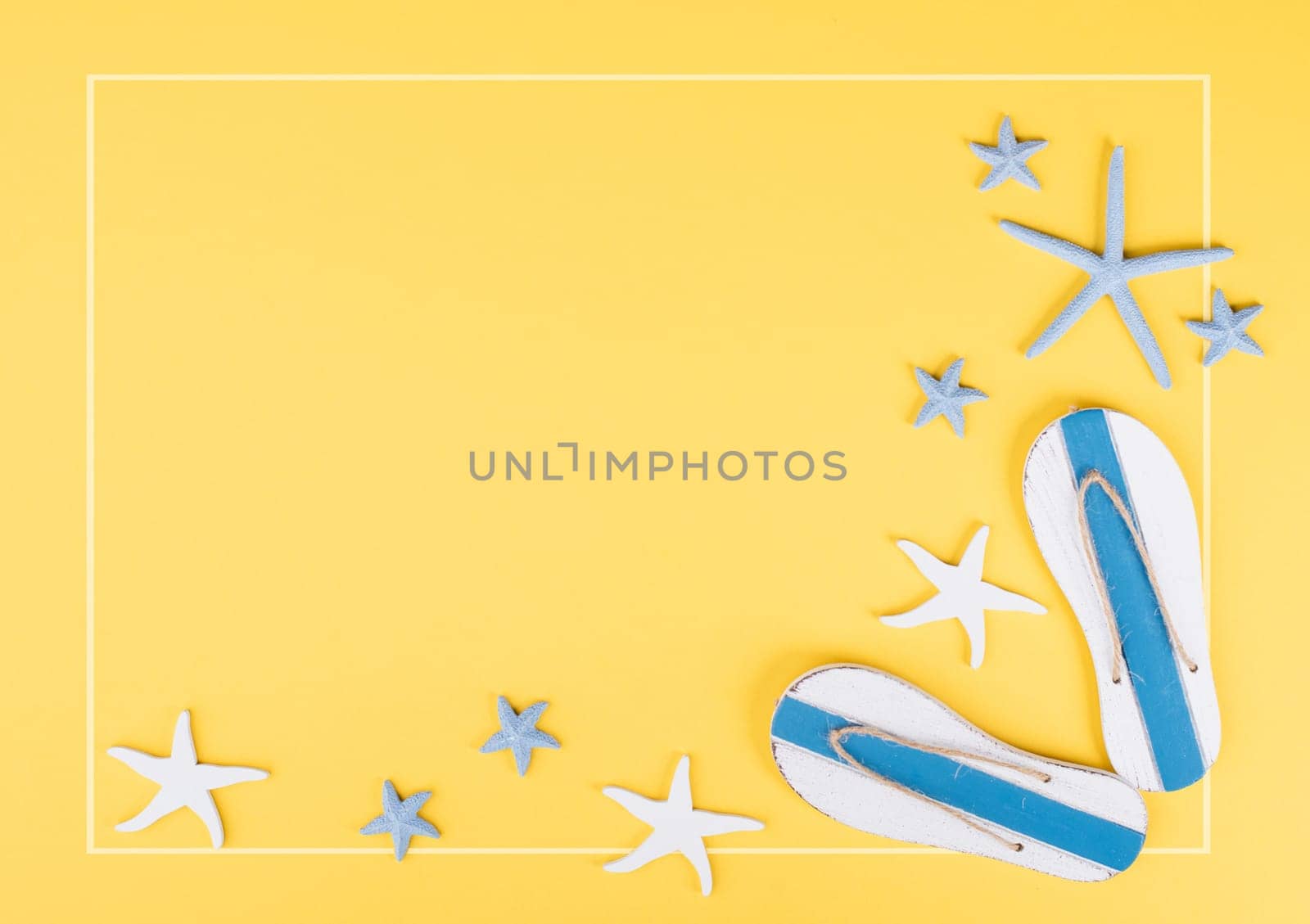 Yellow colored summer and vacation background, slippers and sea stars building a frame, copy space for text, holiday and tourism concept