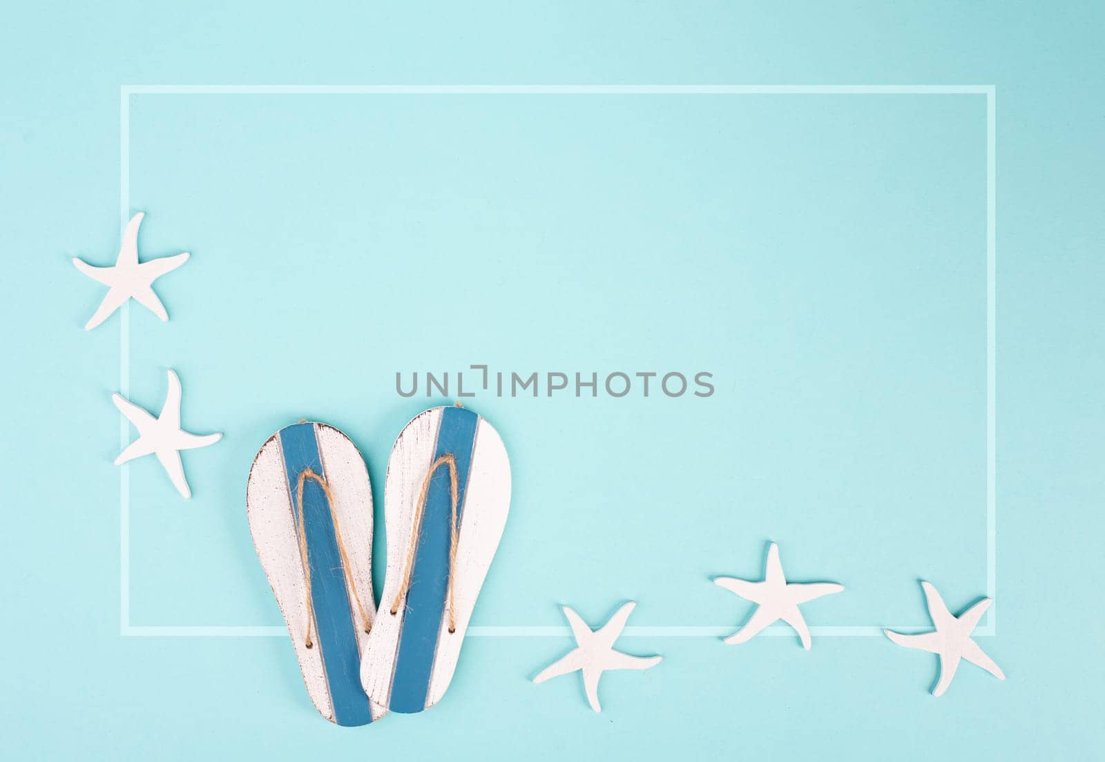 Blue colored summer and vacation background, slippers and sea stars building a frame, copy space for text, holiday and tourism concept