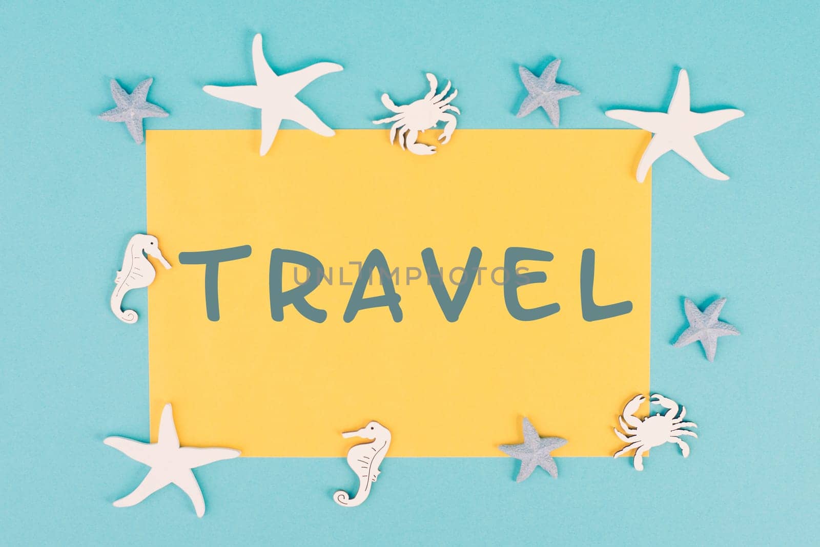 The word travel is standing on a yellow colored paper, sea stars, seahorses and crab bulding a frame, summer vacation, tourism destination