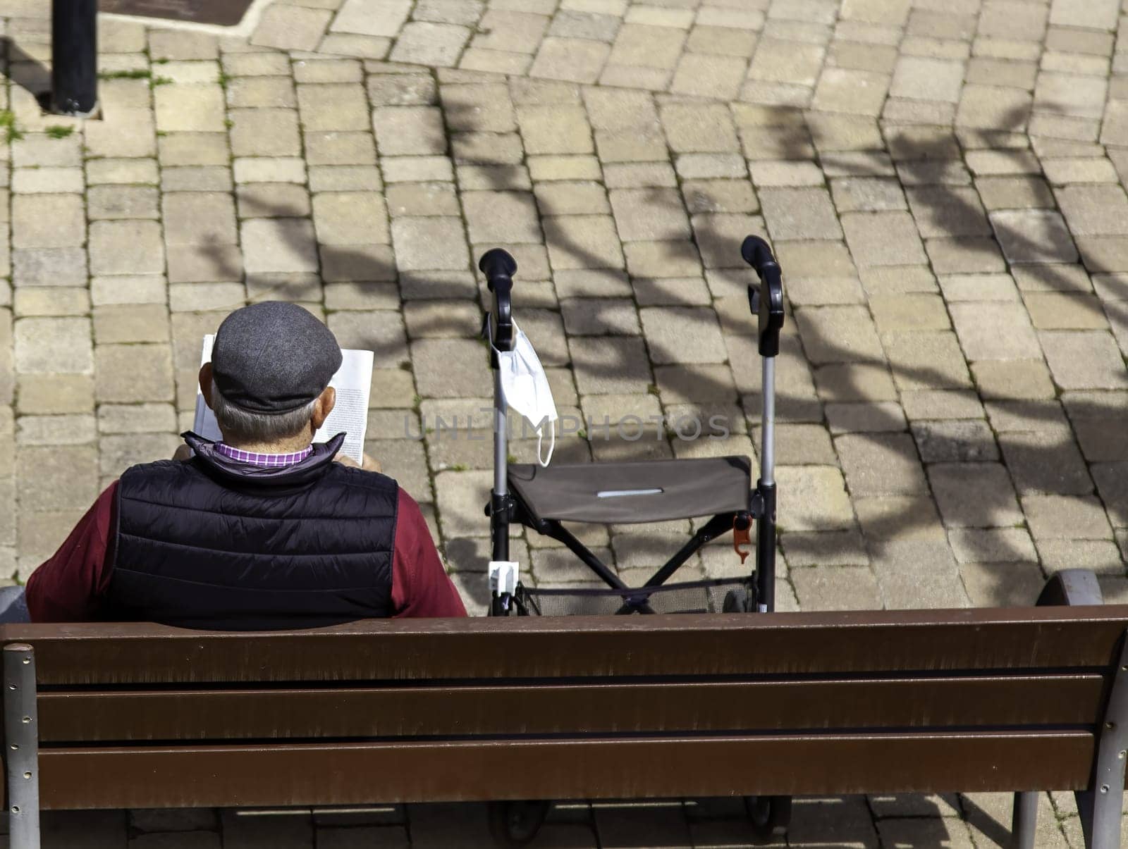 Detail of elderly person resting and reading after a walk
