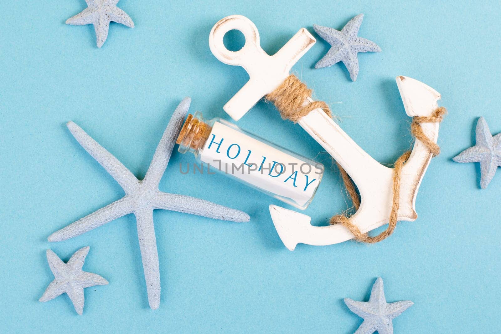 Blue colored summer and vacation background, anchor, sea stars and a glass bootle with the word holiday, travel and tourism concept