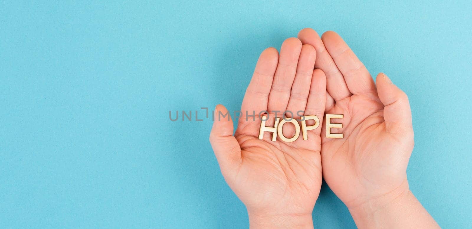 Holding the word hope in the palm of the hands, trust and believe concept, having faith in the future, hopeful positive mindset